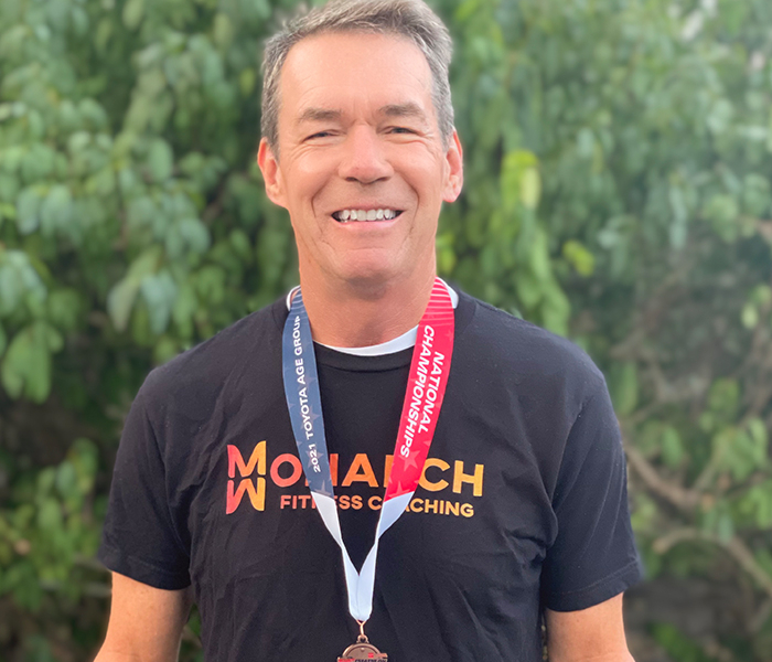 man smiling at camera with fitness medal around neck