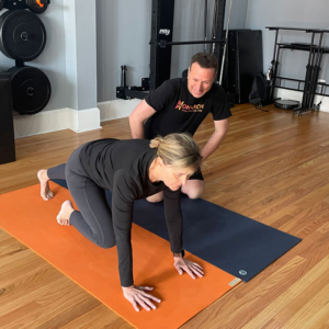 woman on yoga mat with personal trainer